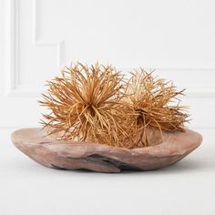 a wooden bowl filled with dry grass on top of a white floor