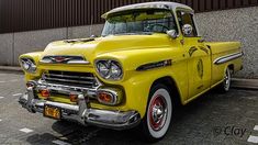 an old yellow truck parked in front of a building with a skull on it's hood