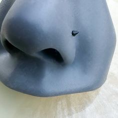 an elephant statue sitting on top of a white table next to a blue vase with a small black object in it's mouth