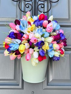 a bucket filled with colorful tulips sitting on top of a door