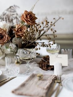 the table is set with silverware and flowers in vases, napkins, and place cards