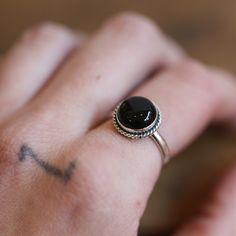 LBJ Pop Rock Ring in Black Agate Everybody loves this Black Agate ring. The black agate stone is always in fashion and always matches! Our Pop Rock Ring lets the 10mm Black Agate be the center of the show! Just right - easy to wear. Enhanced with a simple twist wire, this Black Onyx Ring stands alone or is a fantastic addition to a handful of rings. All .925 Sterling Silver. Choose your size in the drop-down below. All traditional silversmithing is done in our Baltimore Studio. Black Agate 10mm Adjustable Onyx Rings With Black Enamel, Adjustable Black Enamel Onyx Rings, Black Rings With Round Gemstone, Black Oval Agate Jewelry, Gift Black Agate Ring, Minimalist Onyx Gemstone Ring, Black Enamel Onyx Round Rings, Black Agate Round Ring, Adjustable Onyx Rings As Gift