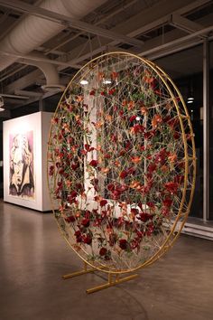 a large metal object with red flowers on it's side in an art gallery