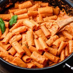 a pan filled with pasta and sauce on top of a wooden table