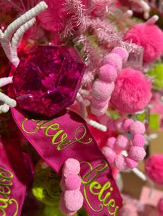 pink and green ornaments with the word hello kitty written on one side, and pom poms in the other