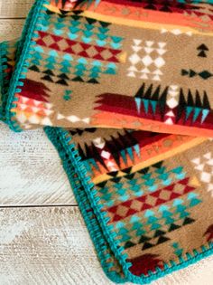 two blankets sitting on top of a wooden floor next to each other with different colored designs