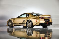 the gold sports car is parked on the reflective surface