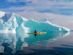 a person in a kayak on the water near an iceberg