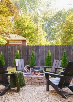 an outdoor fire pit surrounded by lawn chairs and tables with blankets on them in the middle of a gravel area