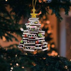 a christmas tree ornament made out of books on a pine tree with lights in the background