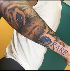 a man with a tiger tattoo on his arm and the word rare written in blue ink