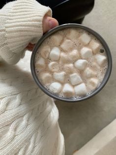 a person holding a cup with marshmallows in it