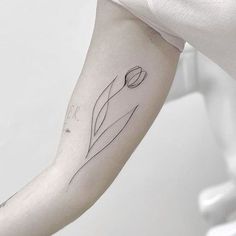 a woman's arm with a single flower tattoo on the left side of her arm