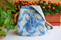 a blue and white purse sitting on top of a table next to potted plants