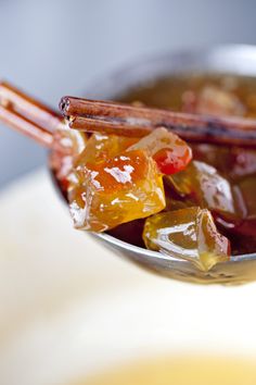 a bowl filled with gummy bears on top of a white countertop next to chopsticks