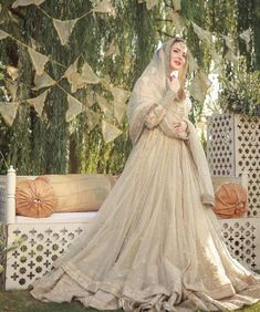 a woman in a wedding dress talking on a cell phone while sitting on a bench