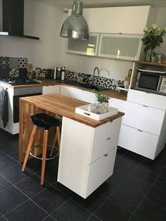 a kitchen with black and white tile flooring and wooden counter tops, an island in the middle