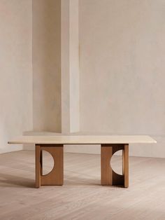 a wooden table sitting on top of a hard wood floor next to a white wall