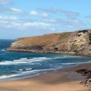 a sandy beach next to the ocean on a sunny day