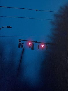 two traffic lights hanging from wires in the dark