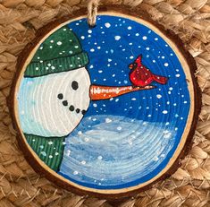 a wooden ornament with a snowman and a cardinal on it