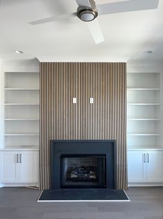 an empty living room with a fireplace and built in bookshelves