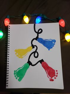 a hand and foot print on a sheet of paper with christmas lights around the edges