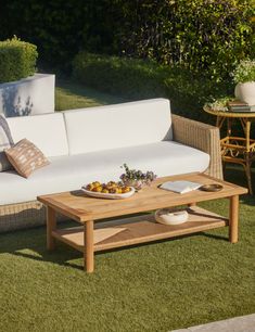 a white couch sitting on top of a green grass covered field next to a wooden table