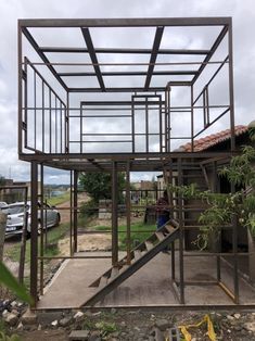 an open metal structure with steps leading up to the top and bottom floor, in front of a house