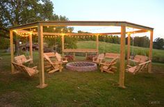 a wooden gazebo with swings and chairs around it in the evening sun, lit by string lights