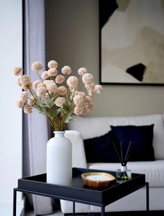 a vase with flowers sitting on a table in front of a couch and coffee table