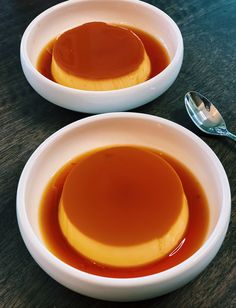 two white bowls filled with caramel sauce on top of a wooden table