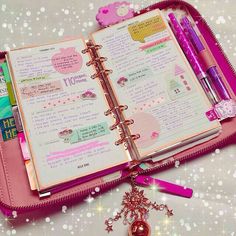 an open pink planner book sitting on top of a table next to a keychain