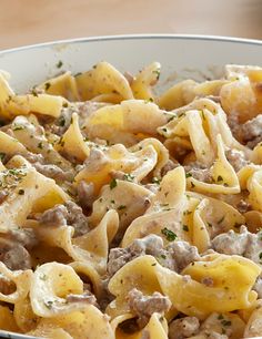 a bowl full of pasta with meat and cheese on the top, sitting on a table