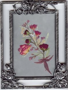 an ornate frame with flowers in it on a gray background and silver trim around the edges