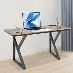 a laptop computer sitting on top of a wooden desk next to a cup of coffee