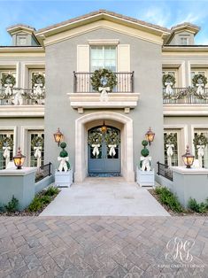 the front entrance to a house decorated with wreaths and teddy bears on balconies