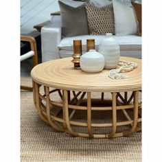 a wicker coffee table with vases on it in front of a white couch