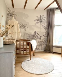 a baby's room with a crib, dresser and wallpaper