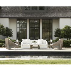 a white couch sitting on top of a patio next to a pool in front of a house