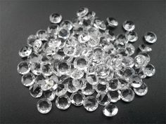 clear glass beads are scattered on a black surface, with small holes in the middle