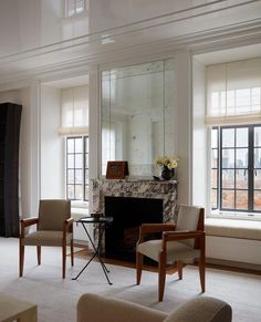 a living room filled with furniture and a fire place in front of a mirror on the wall