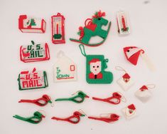 a collection of cross stitch christmas ornaments on a white surface with scissors and other items