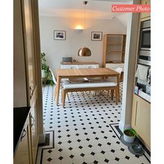 an open door leading to a dining room with black and white floor tiles on the walls