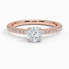 a rose gold engagement ring with diamonds on the band and a round cut diamond in the center