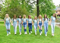 a group of young women standing next to each other on top of a lush green field