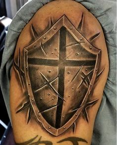 a man with a cross and shield tattoo on his arm