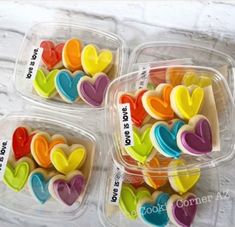 three plastic containers filled with heart shaped cookies on top of a white marble countertop