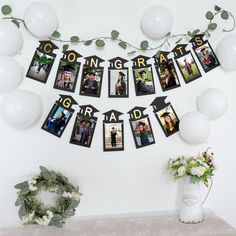 an arrangement of photos hanging on a mantle with balloons and greenery in the background