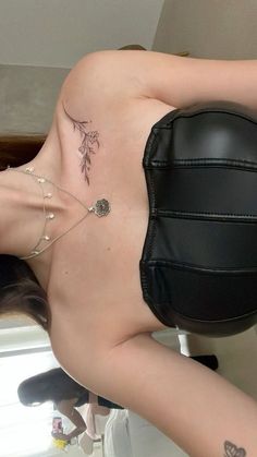 a woman with tattoos on her back is sitting in front of a mirror and wearing a black leather chair